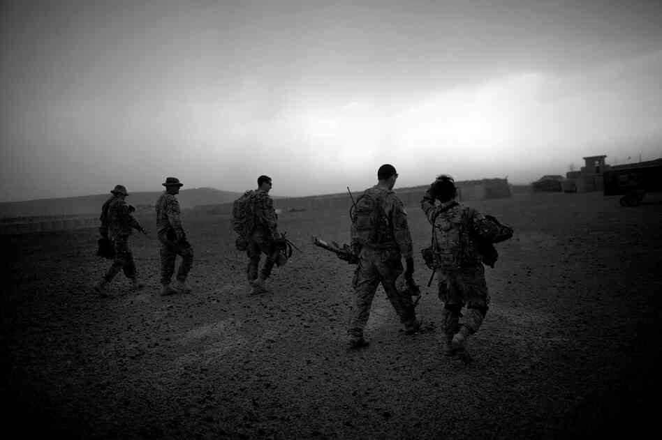 Soldiers walk through a driving rainstorm on the landing zone of Forward Operating Base Giro.