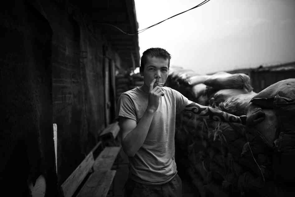 Derik Moe, of Pasco, Wash., smokes a cigarette behind the sandbag walls of makeshift sleeping quarters, located in an old office building.