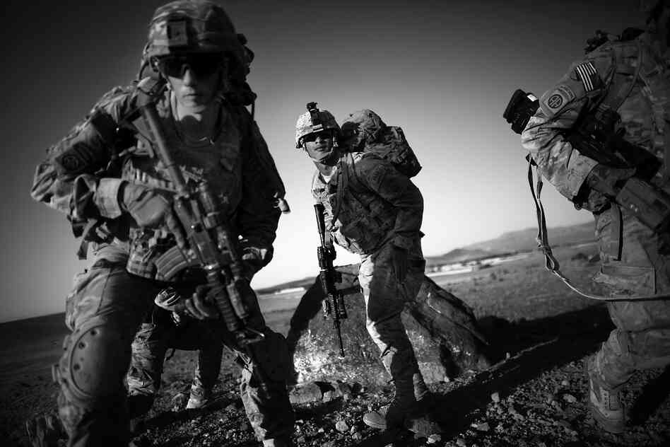Pfc. Habeeb Al-Mashala (left) of Detroit and Medic Spc. Chris Green of San Antonio pull away from an overwatch position as other members of their team move on a trail below.