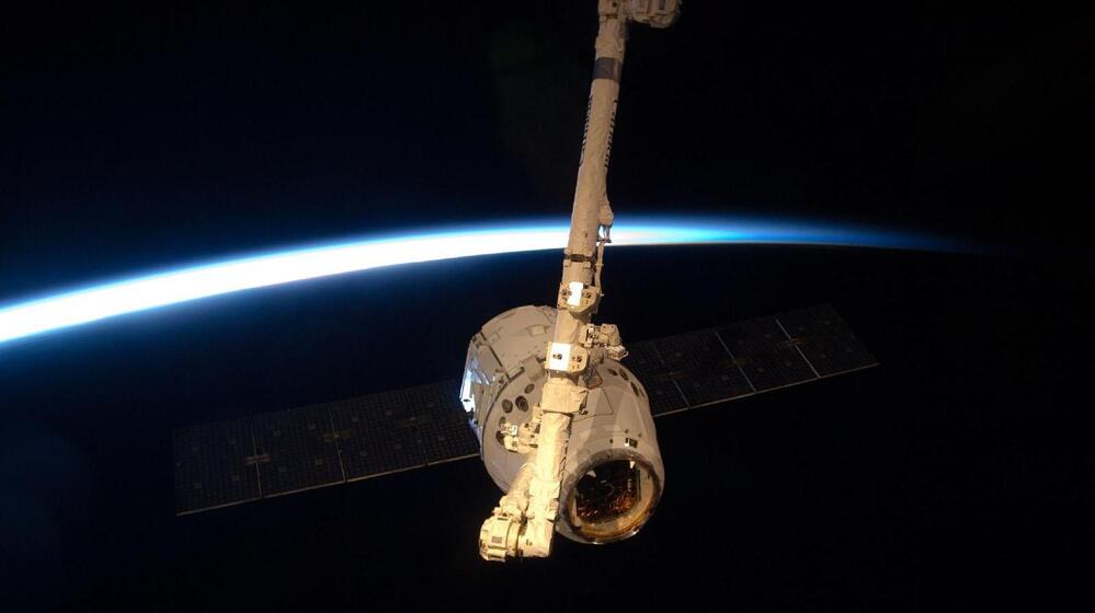 The SpaceX Dragon module, held by the International Space Station's robotic arm.