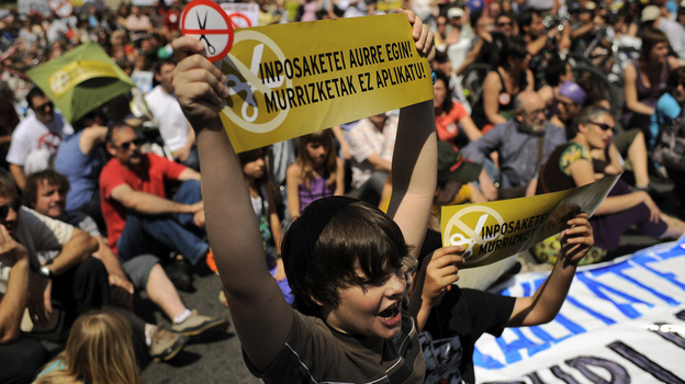 A student in Pamplona, holding a sign in the Basque language, protests cuts Thursday in education and other public services by the government. Spain's financial position is weakening and there are fears the country will need a bailout.