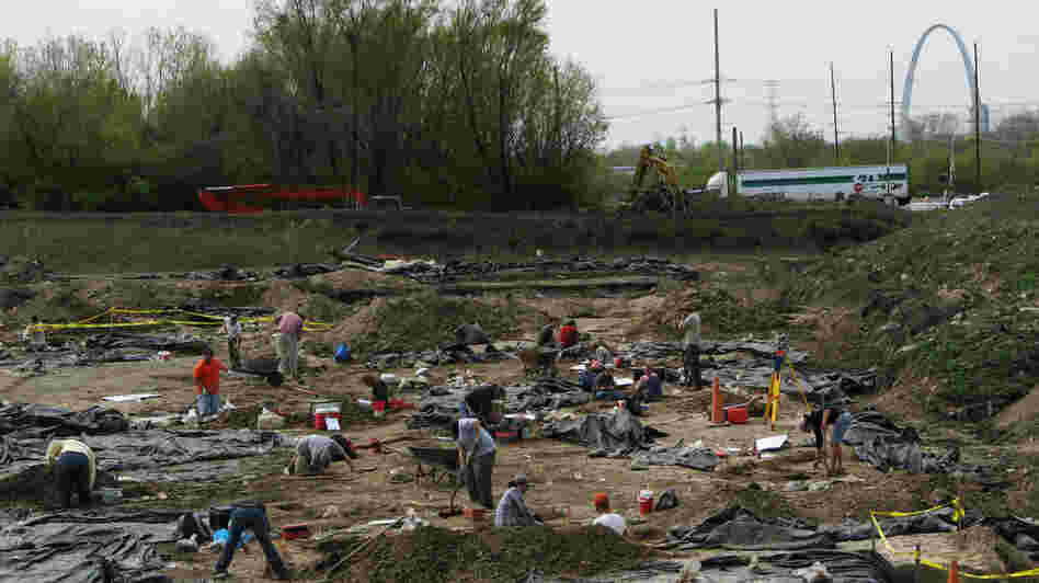 Archaeologists and crew members from the Illinois State Archaeological Survey work at an East St. Louis dig site, which is believed to be a suburb of the ancient city of Cahokia. Black plastic sheeting protects the excavations. In the distance, construction crews are building a stretch of interstate freeway leading to a new Mississippi River bridge. Archaeologists and crew members from the Illinois State Archaeological Survey work at an East St. Louis dig site, which is believed to be a suburb of the ancient city of Cahokia. Black plastic sheeting protects the excavations. In the distance, construction crews are building a stretch of interstate freeway leading to a new Mississippi River bridge.