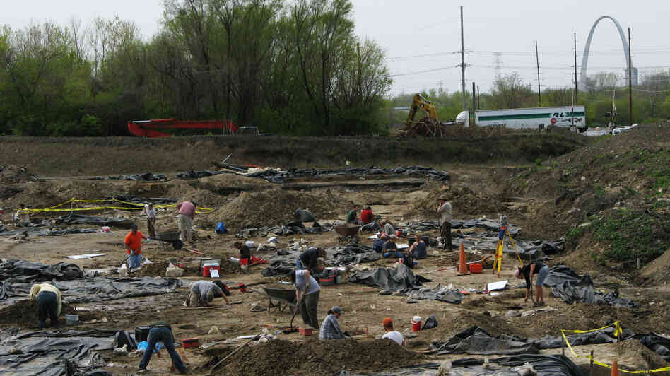 Archaeologists and crew members from the Illinois State Archaeological Survey work at an East St. Louis dig site, which is believed to be a suburb of the ancient city of Cahokia. Black plastic sheeting protects the excavations. In the distance, construction crews are building a stretch of interstate freeway leading to a new Mississippi River bridge. Archaeologists and crew members from the Illinois State Archaeological Survey work at an East St. Louis dig site, which is believed to be a suburb of the ancient city of Cahokia. Black plastic sheeting protects the excavations. In the distance, construction crews are building a stretch of interstate freeway leading to a new Mississippi River bridge.