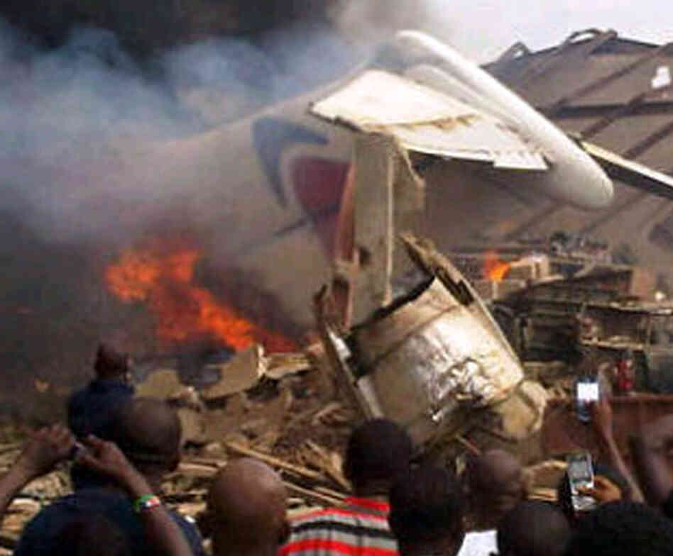 A picture taken with a photo camera shows residents of the Iju district of Lagos, Nigeria,  gathering at the site where a Dana Air jet crashed into a neighborhood on Sunday.