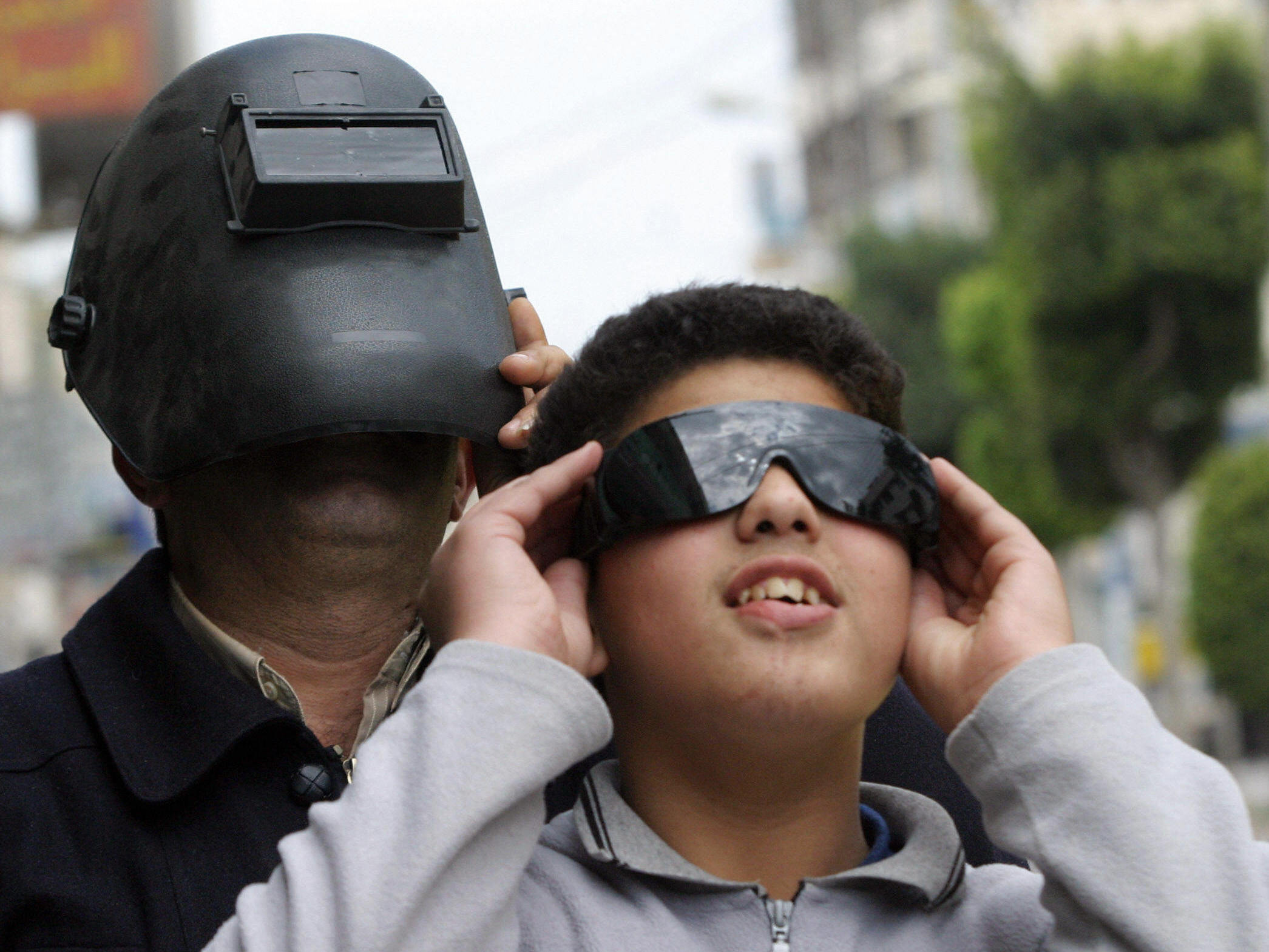 Safety over style: In 2006, a Palestinian man and boy were careful to protect their eyes while watching a partial eclipse of the sun. The same cautions are in order for Venus' transit of the sun on Tuesday.