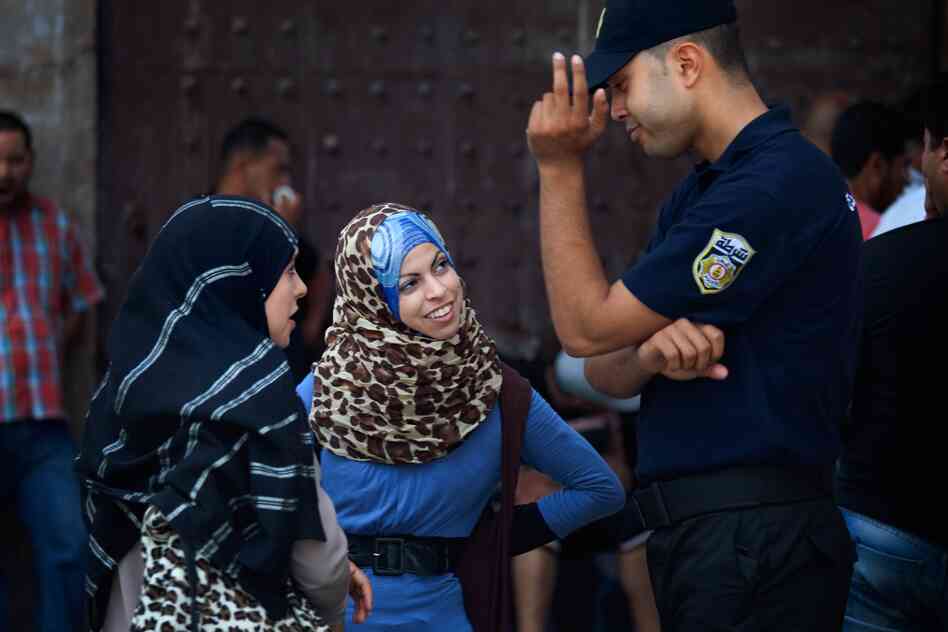 Women talk with a police officer in Tunis.