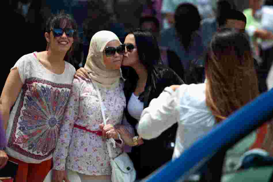 Women in a range of styles pose for a picture near the entrance to the old medina, or marketplace, in Tunis.