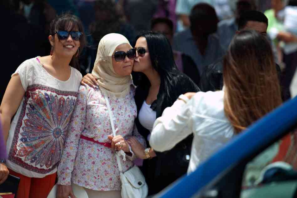 Women in a range of styles pose for a picture near the entrance to the old medina, or marketplace, in Tunis.