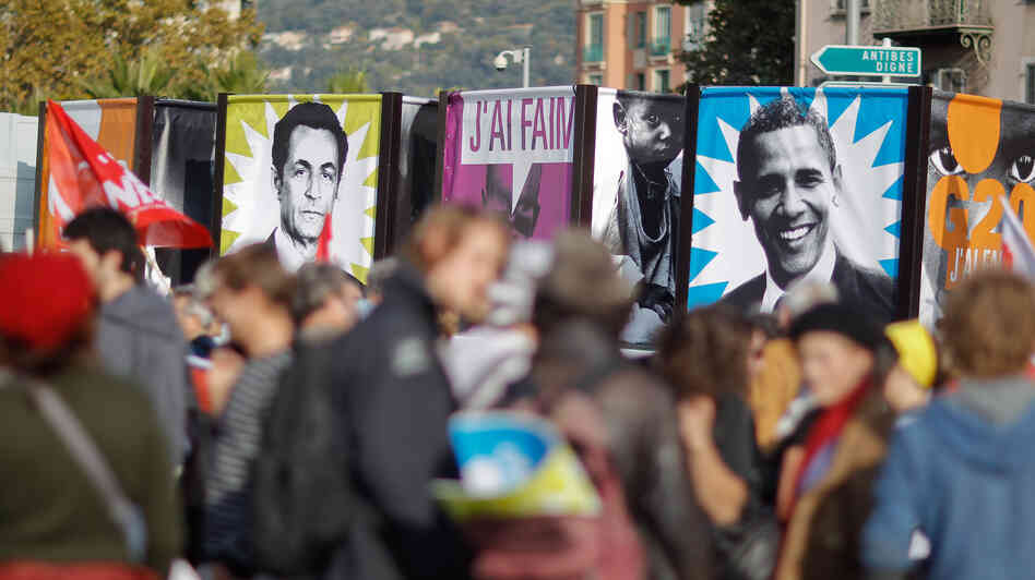 Protesters in Nice, France, hold banners depicting then-French President Nicolas Sarkozy and President Obama before a November 2011 G-20 summit where global financial issues were discussed. Sarkozy has since lost re-election; some political scientists say economic problems in Europe also could play an unprecedented role in the upcoming U.S. election.