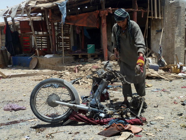 An Afghan man inspects a motorcycle used in today's suicide attack near Kandahar.