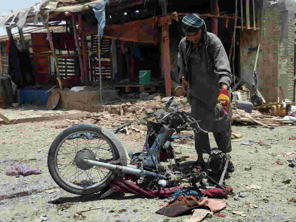 An Afghan man inspects a motorcycle used in today's suicide attack near Kandahar.