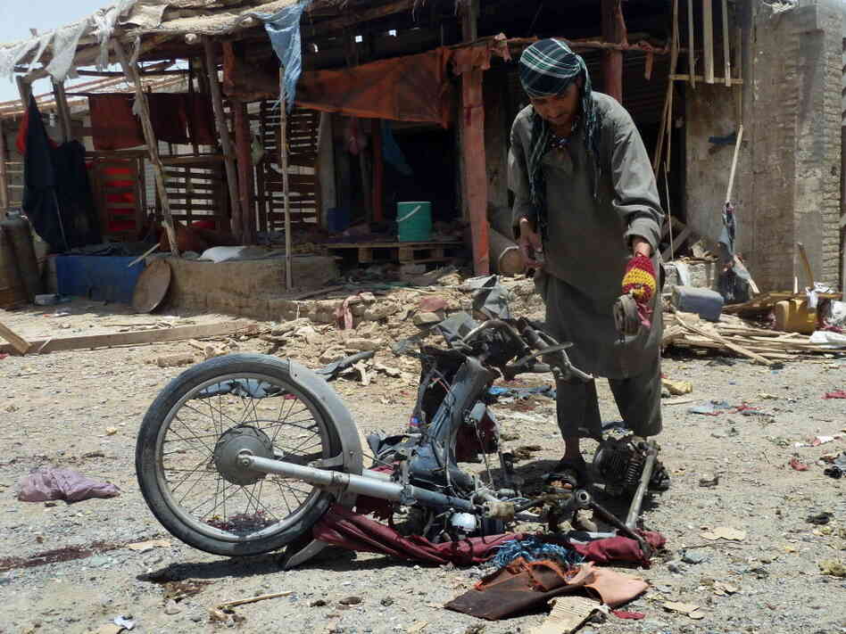 An Afghan man inspects a motorcycle used in today's suicide attack near Kandahar.