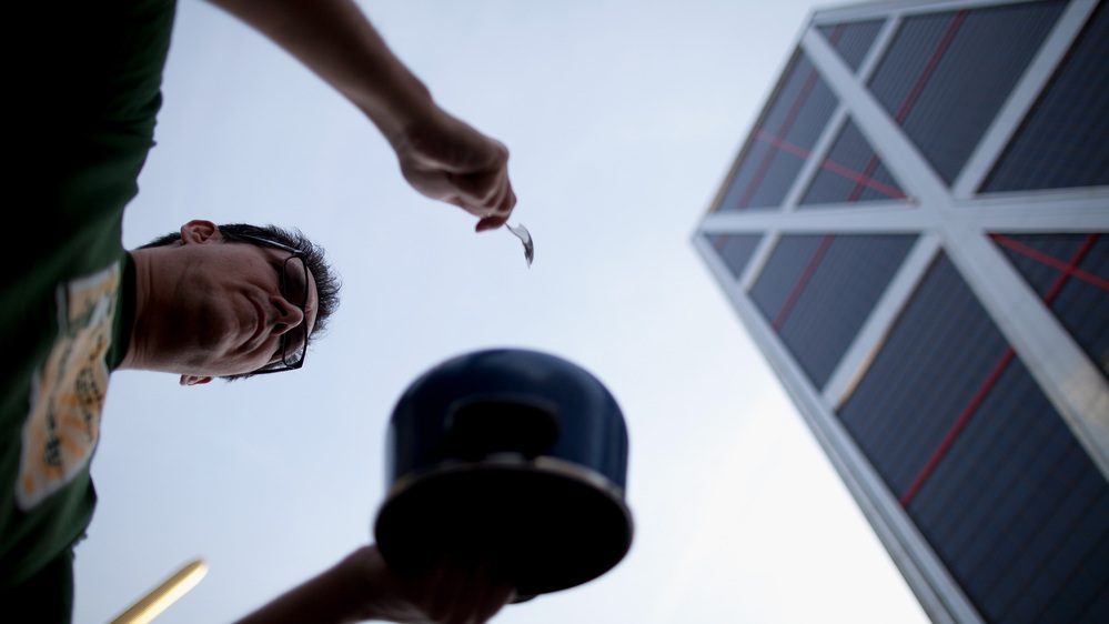 A Spanish protester bangs on a pot outside the offices of Bankia in Madrid. Spain's banks are hurting and in need of an infusion of capital.