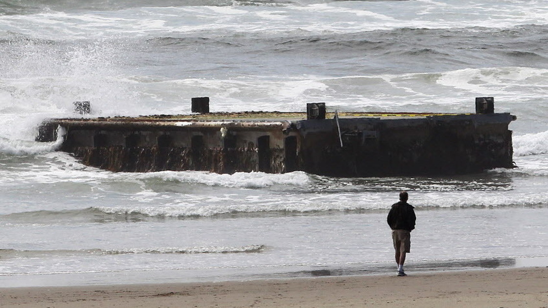 A man looks at the massive dock from Japan that washed ashore on Oregon's Agate Beach this week.