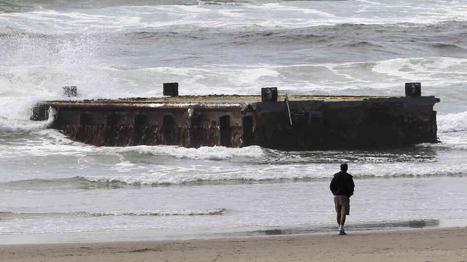 A man looks at the massive dock from Japan that washed ashore on Oregon's Agate Beach this week.