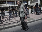 An elderly man walked by riot policemen guarding the Interior Ministry in Athens on Wednesday. An elderly man walked by riot policemen guarding the Interior Ministry in Athens on Wednesday.