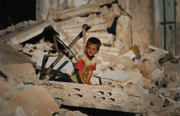 A Syrian boy sits in the rubble of house which was destroyed during a military operation by the Syrian pro-Assad army in April in the town of Taftanaz, Syria.
