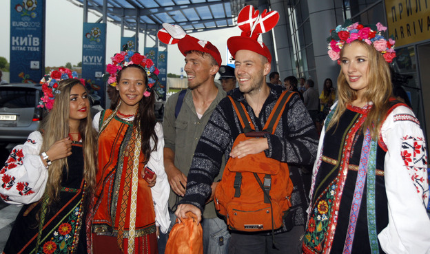 Soccer fans pose with Ukrainian girls dressed in traditional costumes at the airport in Kiev, the capital, Wednesday. The former Soviet state, together with Poland, is co-hosting the Euro 2012 soccer championship.