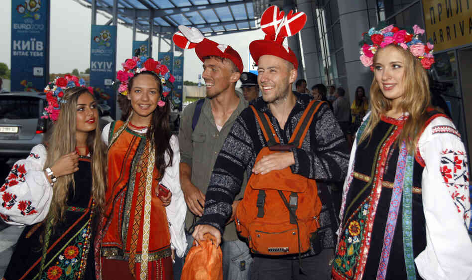 Soccer fans pose with Ukrainian girls dressed in traditional costumes at the airport in Kiev, the capital, Wednesday. The former Soviet state, together with Poland, is co-hosting the Euro 2012 soccer championship.