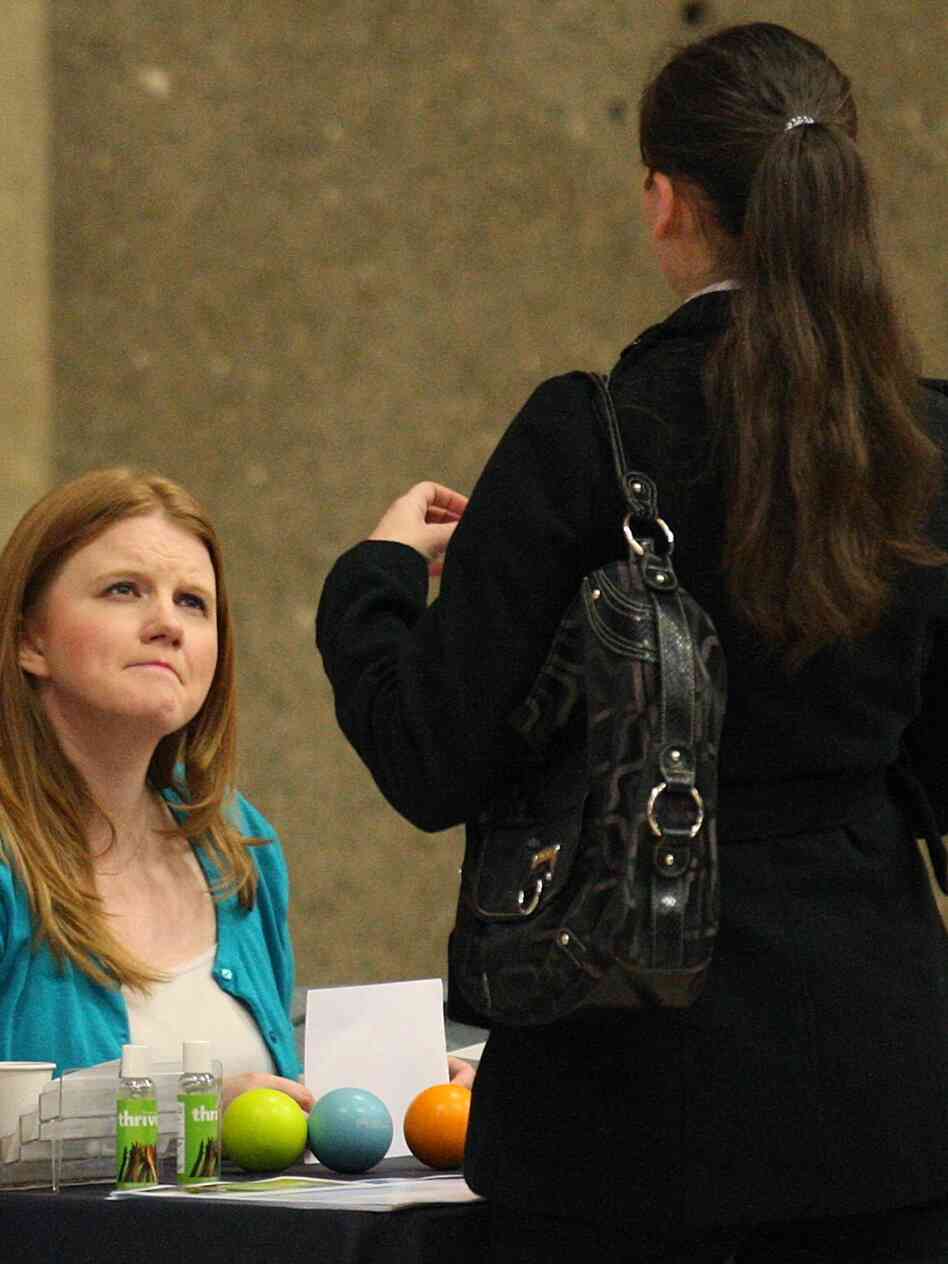 A recruiter (left) talks with a job seeker at an Oregon job fair. Job growth slowed in May, and some employers say economic uncertainty has left them reluctant to hire.