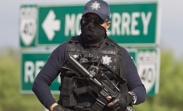 A Mexican federal policeman guards the area where dozens of bodies, some of them mutilated, were found on a highway outside the northern Mexican city of Monterrey on  May 13. The murders were one of the latest episodes in Mexico's brutal and unrelenting drug war.