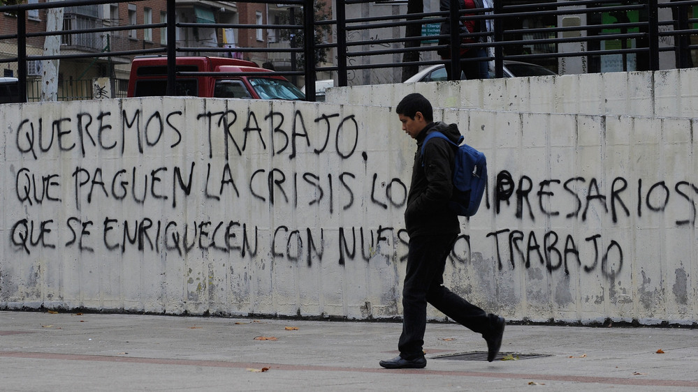 Graffiti on a wall in Madrid reads, "We want to work, let the businessmen who have gotten rich from our labor pay for the crisis." Nearly 50 percent of young adults in Spain are unemployed.