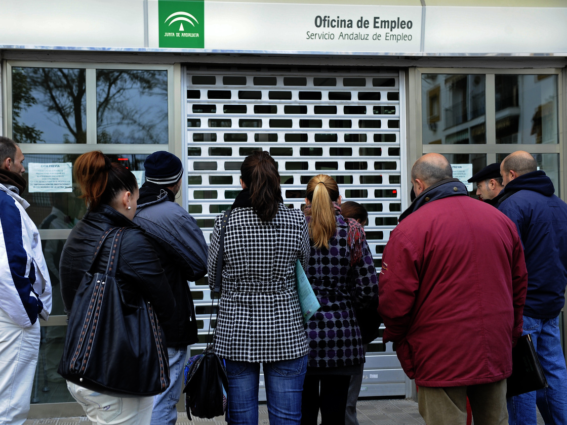 People wait in line in front of a government employment office in the Cruz Roja suburb of Sevilla.