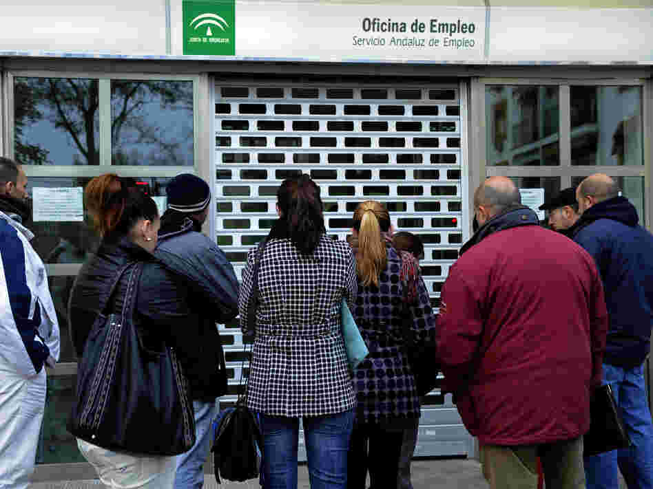 People wait in line in front of a government employment office in the Cruz Roja suburb of Sevilla.