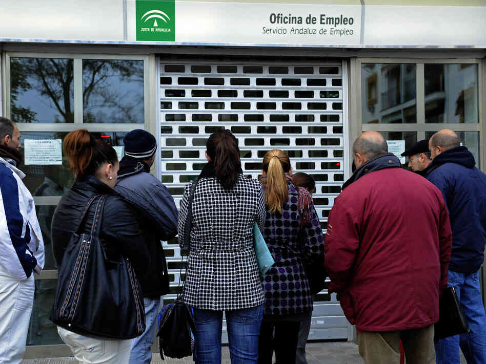 People wait in line in front of a government employment office in the Cruz Roja suburb of Sevilla.