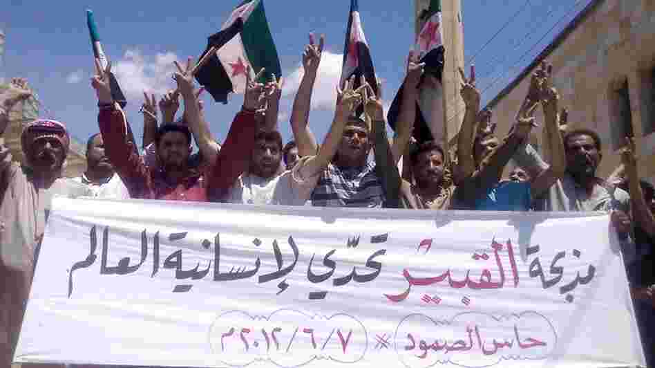 Anti-government protesters in the northern Syrian village of Hass protest on Thursday following the deaths of dozens of civilians a day earlier in the village of Mazraat al-Qubair. The banner reads, "The al-Qubair massacre challenges the world's humanity."