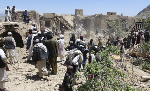 In this Wednesday, June 6, 2012 file photo, Afghan villagers gather near a house destroyed in an apparent NATO raid in Logar province, south of Kabul, Afghanistan.