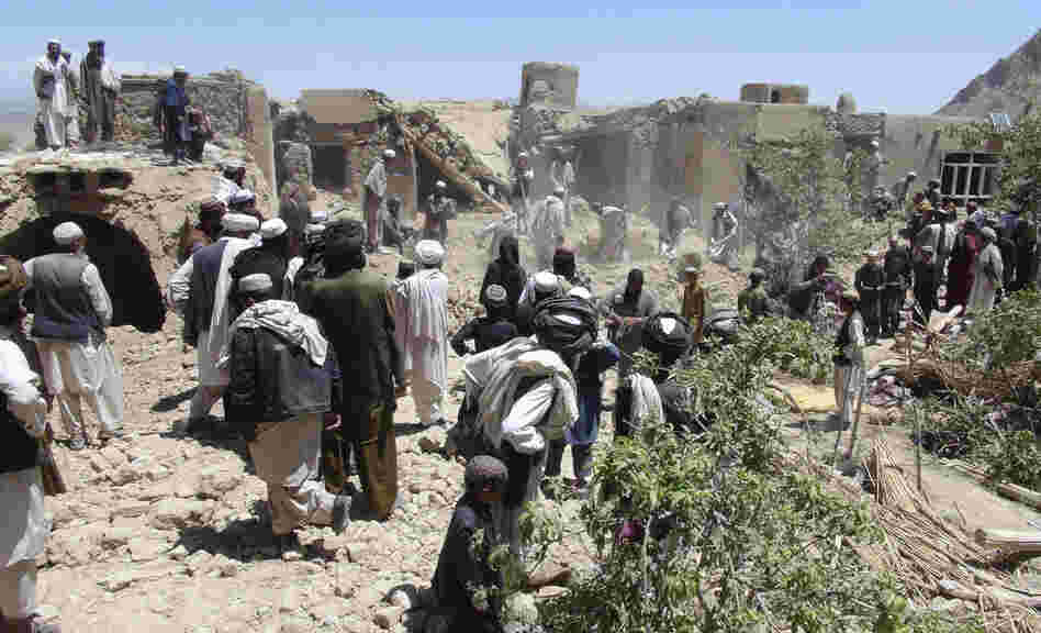 In this Wednesday, June 6, 2012 file photo, Afghan villagers gather near a house destroyed in an apparent NATO raid in Logar province, south of Kabul, Afghanistan.