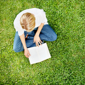 A woman reads a book in the grass