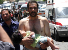 A Syrian man carries a wounded girl next to Red Crescent ambulances following an explosion Friday reportedly targeting a military bus near Qudssaya, a neighborhood in Damascus. A Syrian man carries a wounded girl next to Red Crescent ambulances following an explosion Friday reportedly targeting a military bus near Qudssaya, a neighborhood in Damascus.