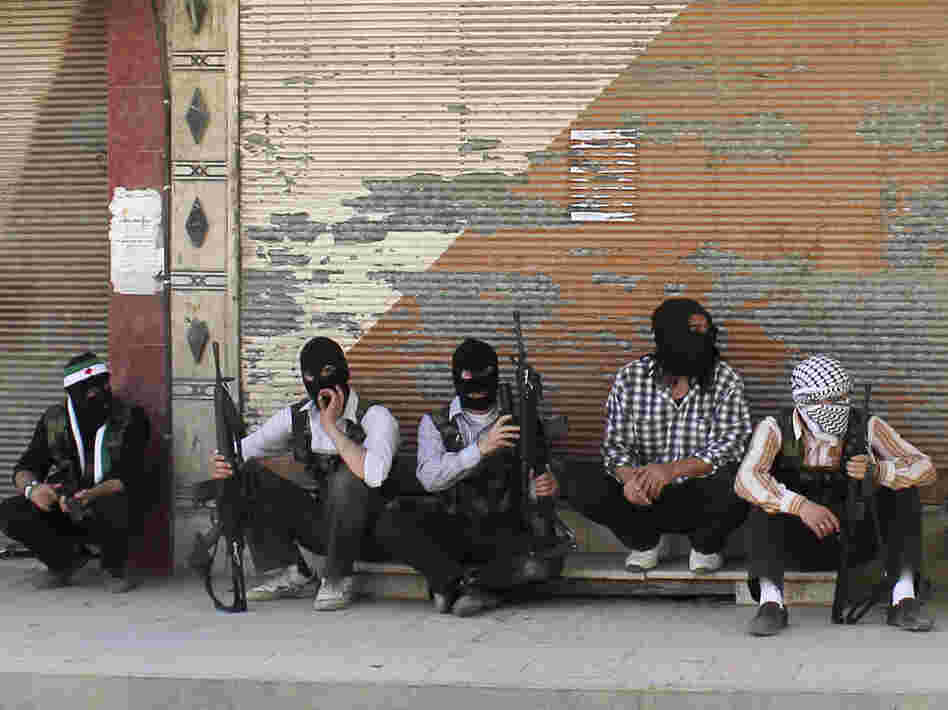 Free Syrian Army members, with covered faces and holding weapons, sit by the side of a street Monday in the Qaboon district in Damascus. Free Syrian Army members, with covered faces and holding weapons, sit by the side of a street Monday in the Qaboon district in Damascus.