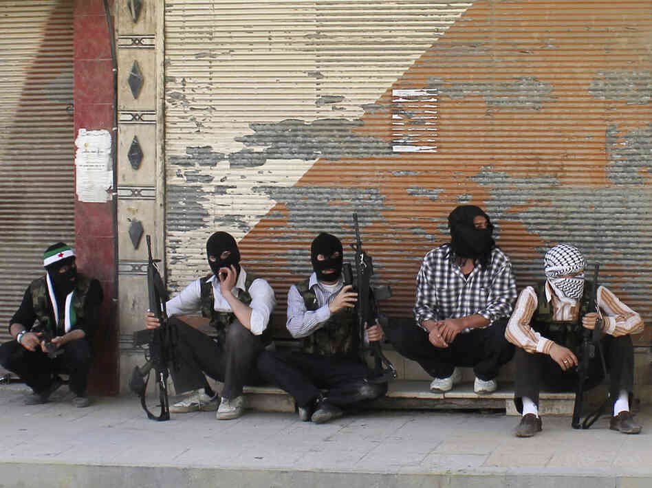 Free Syrian Army members, with covered faces and holding weapons, sit by the side of a street Monday in the Qaboon district in Damascus. Free Syrian Army members, with covered faces and holding weapons, sit by the side of a street Monday in the Qaboon district in Damascus.