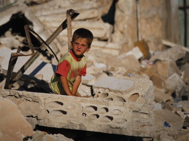 A Syrian boy sits in the rubble of house destroyed during a military operation in April in the town of Taftanaz, Syria.