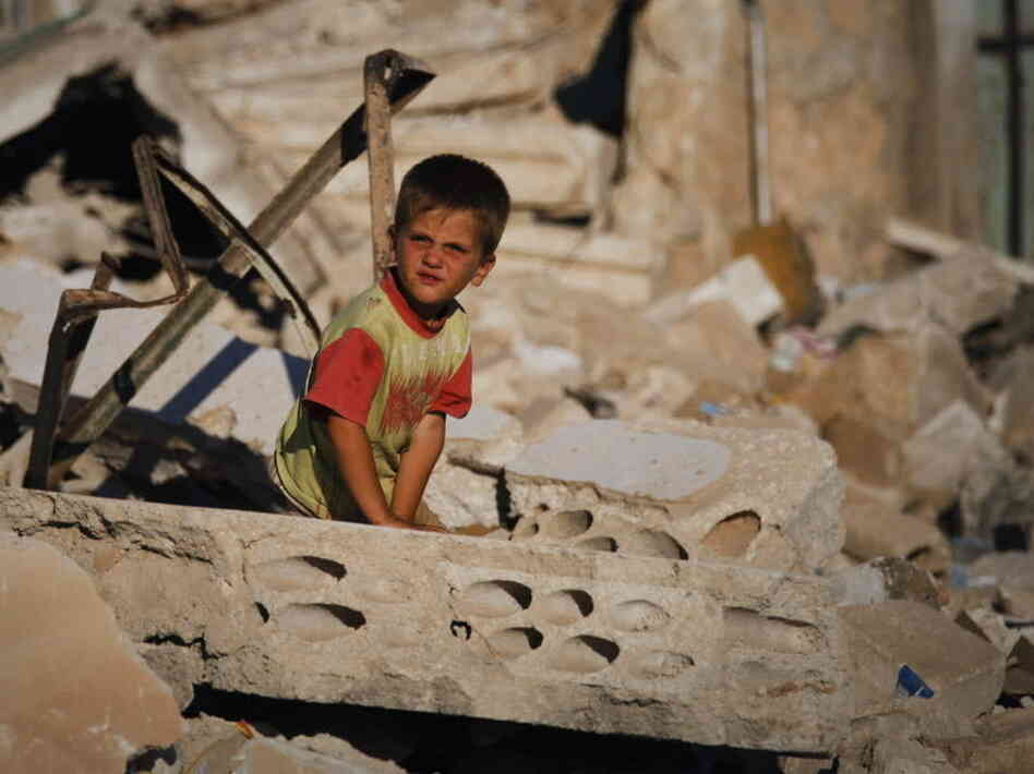 A Syrian boy sits in the rubble of house destroyed during a military operation in April in the town of Taftanaz, Syria.
