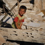 A Syrian boy sits in the rubble of house destroyed during a military operation in April in the town of Taftanaz, Syria.