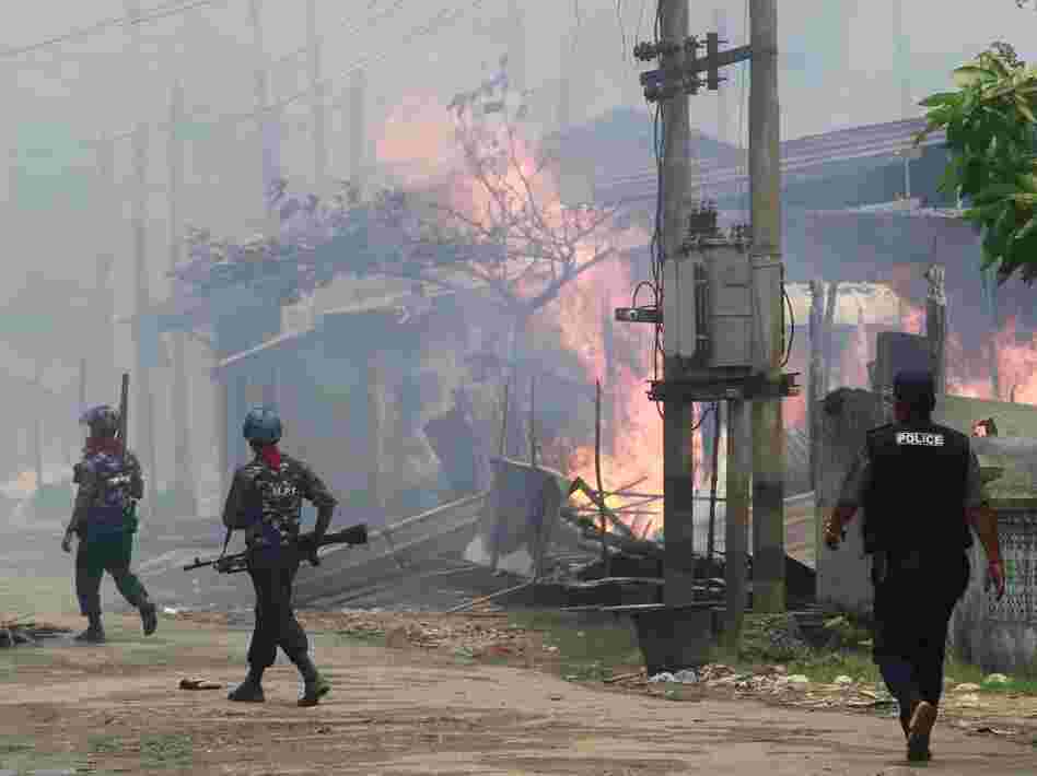 Policemen in Myanmar walk toward burning buildings in the town of Sittwe, in the western part of the country, where Muslims and Buddhists have clashed recently.