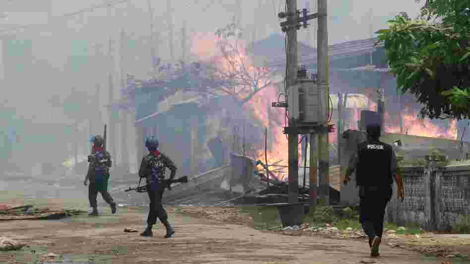 Policemen walk toward burning buildings in Sittwe, where some residents fled burning homes and gunshots as deadly ethnic violence broke out.