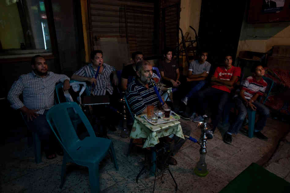At the market, a small group gathers to watch England play France in a soccer match at the European championship. They're rooting for England.