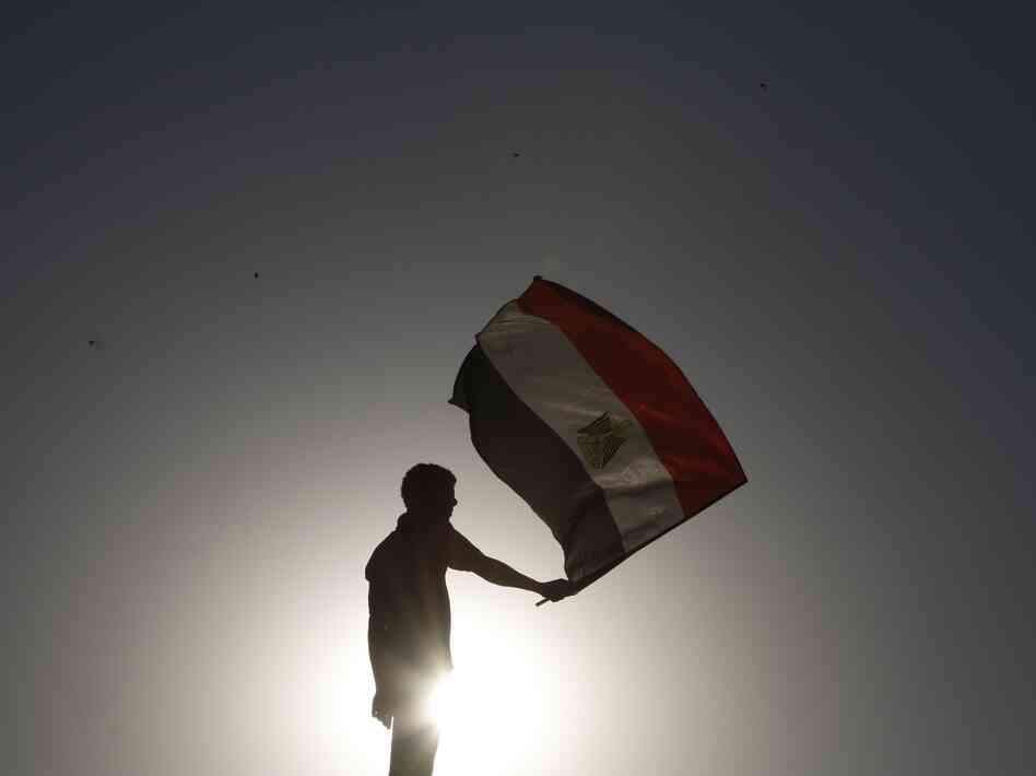 An Egyptian protester waves his national flag at sunset during a demonstration in Cairo's landmark Tahrir Square on June 5, 2012 to protest against verdicts handed down in ex-president Hosni Mubarak's murder trial.