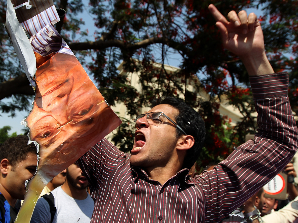 An Egyptian protester chants slogans as he holds a ripped poster of presidential candidate Ahmed Shafiq outside the Supreme Constitutional Court in Cairo today.