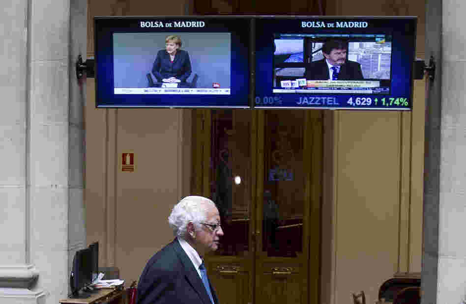German Chancellor Angela Merkel is seen on a screen as a broker arrives at the stock exchange in Madrid on Thursday.