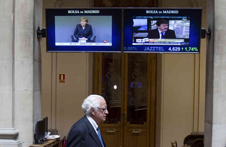 German Chancellor Angela Merkel is seen on a screen as a broker arrives at the stock exchange in Madrid on Thursday.