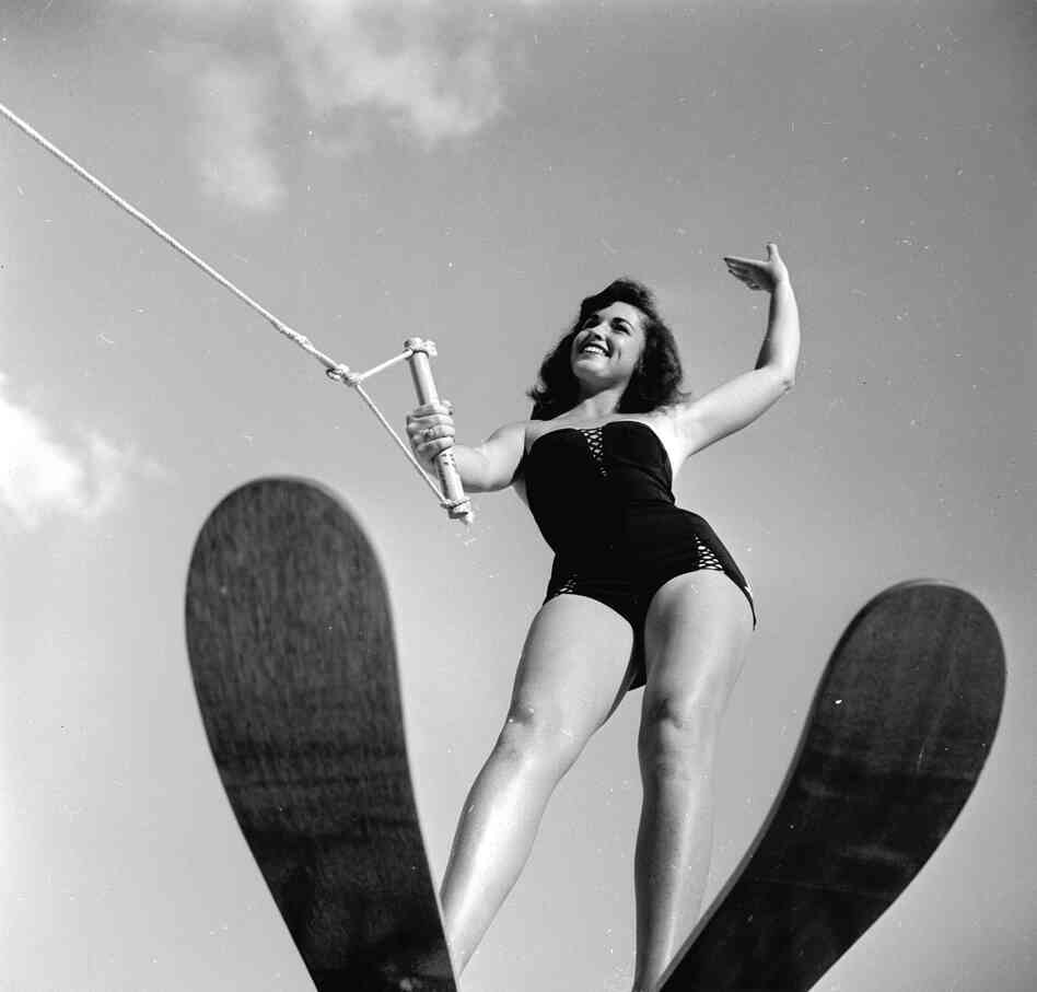 A swimsuit model poses on water skis while still on dry land in 1955.
