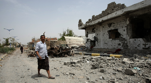 Yemeni residents walk past vehicles and houses which were destroyed during recent fighting between the army and militants on a road leading to the city of Zinjibar on Thursday.