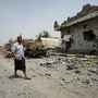 Yemeni residents walk past vehicles and houses which were destroyed during recent fighting between the army and militants on a road leading to the city of Zinjibar on Thursday.