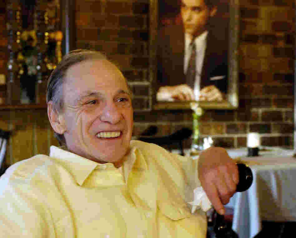 Henry Hill sits in the dining room of the Firefly restaurant in North Platte, Neb., in 2005. A portrait of actor Ray Liotta portraying Hill in the movie Goodfellas hangs on the wall behind him.